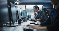 Porträt eines nachdenklichen Ingenieurs, der an einem Desktop-Computer in einer technologischen Büroumgebung arbeitet.