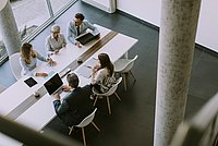 Luftaufnahme bei einer Gruppe von Geschäftsleuten, die zusammenarbeiten und ein neues Projekt für ein Meeting im Büro vorbereiten