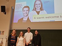 Auf dem Podium stehen die Referenten.